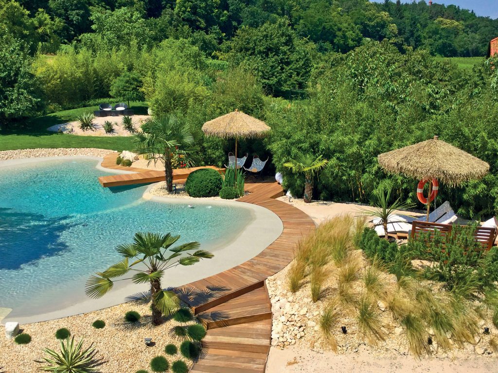 Piscine lagon paysagère intégrée à un domaine hôtelier haut de gamme en Rhone Alpes ambiance coucher de soleil, réalisation Florasol