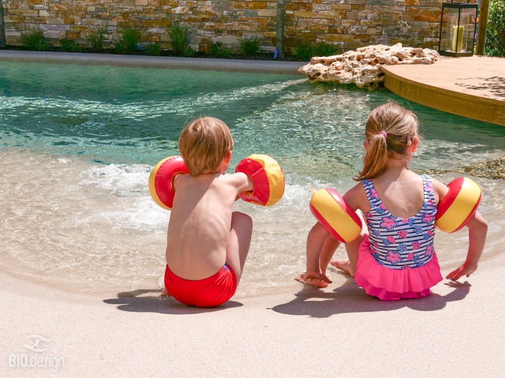 Enfants profitant d'une plage immergée dans une piscine lagon Bio.design avec entrée progressive dans l'eau