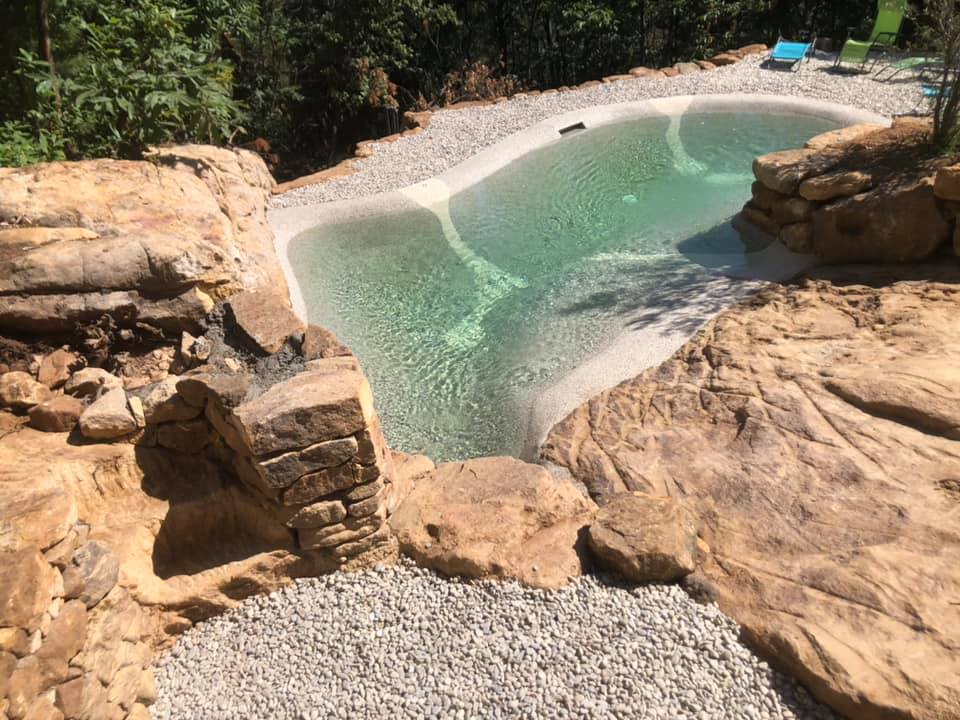 Piscine lagon Bio.design réalisée par Florasol sur terrain rocheux en Ardèche avec intégration des rochers naturels