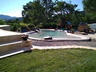 Lagon Bio.design intégré dans un jardin paysager avec vue sur les reliefs ardéchois