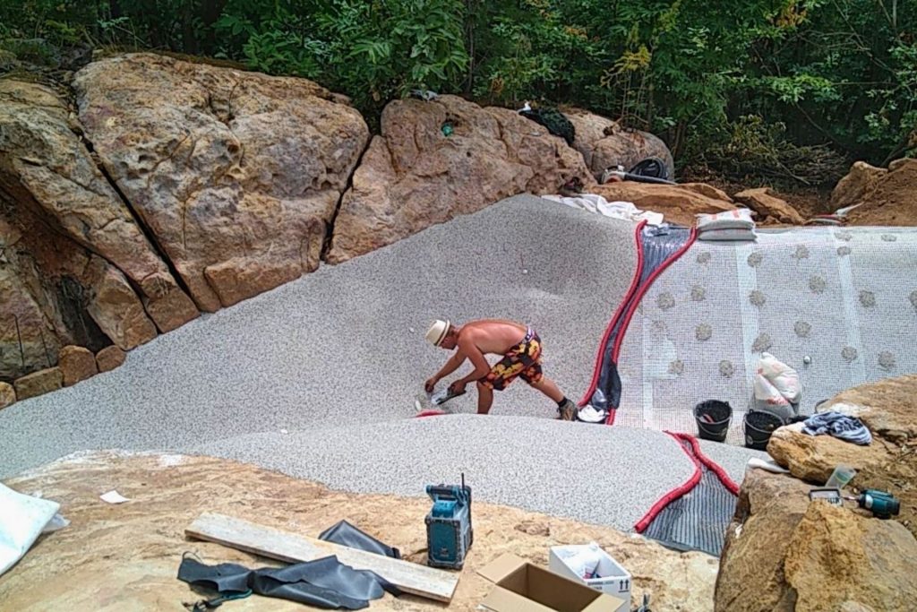 Application manuelle du revêtement minéral en quartz sur une piscine lagon Bio.design réalisée par Florasol en Ardèche