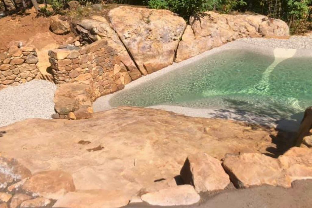Piscine lagon Bio.design construite autour d'un massif rocheux naturel en Ardèche