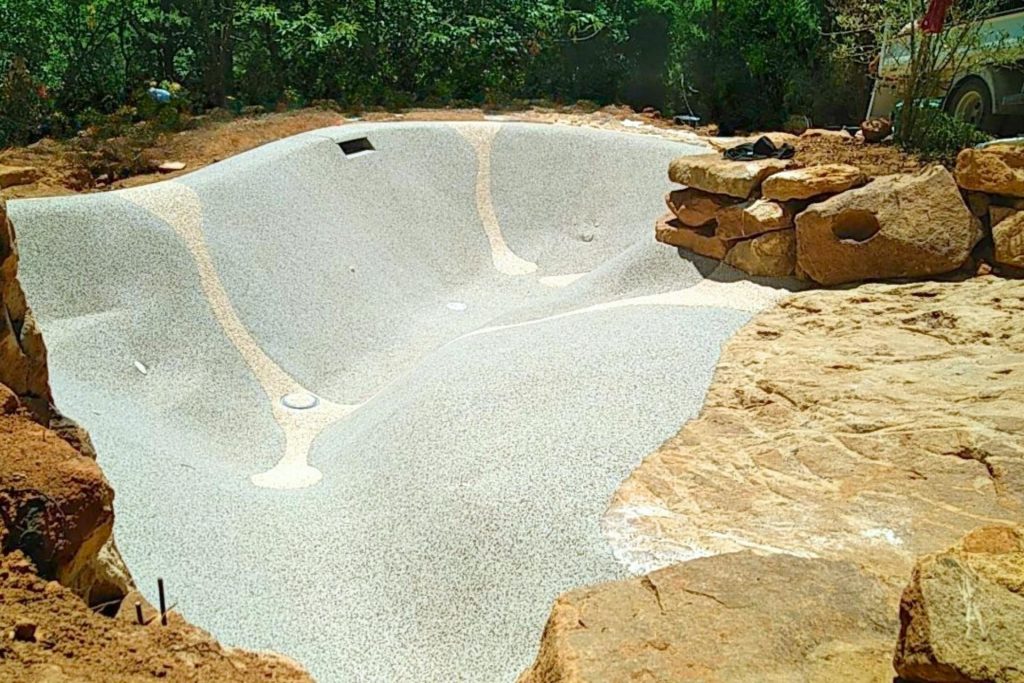 Plage immergée et courbes naturelles d'une piscine lagon Bio.design en cours de réalisation en Ardèche