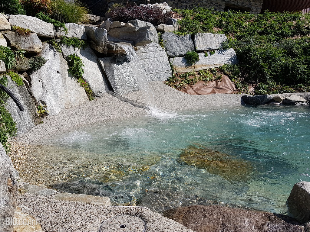 Piscine lagon Bio.design avec cascade en pierre naturelle et intégration paysagère sur terrain rocheux