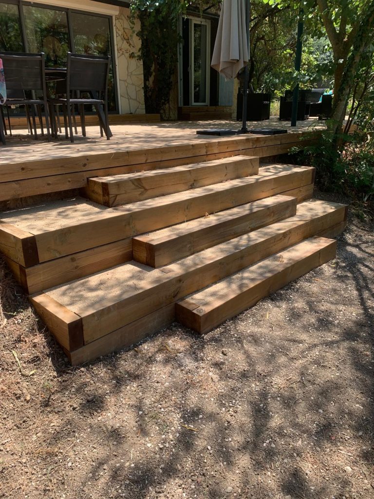 Escalier paysager terminé avec poutres bois et marches en résine minérale devant une terrasse Thermopin® en Ardèche.