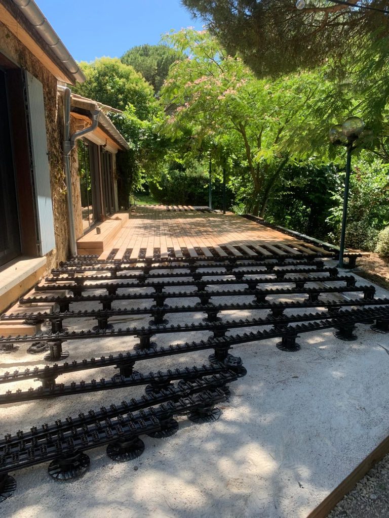 Installation du système Grad® avec plots réglables et rails aluminium avant la pose d'une terrasse en bois Thermopin® haut de gamme en Ardèche.