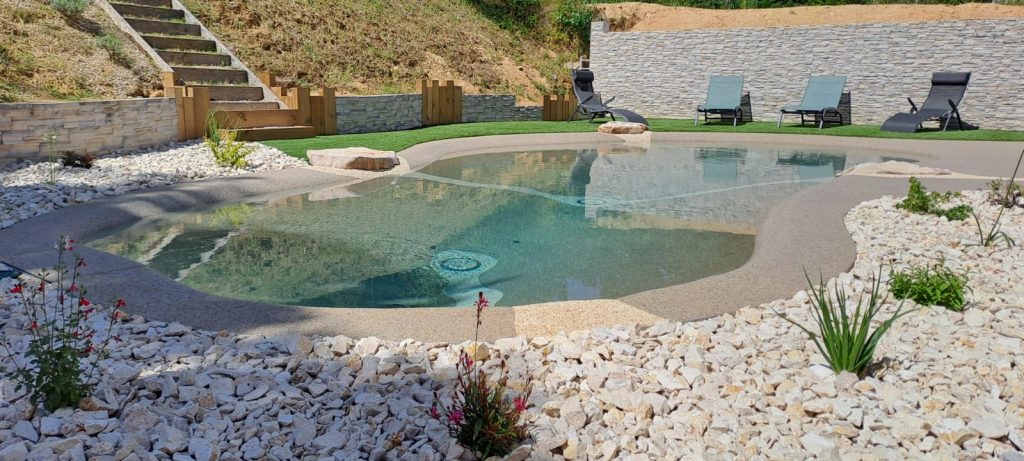 Piscine lagon avec massif en pierre blanche et aménagement paysager